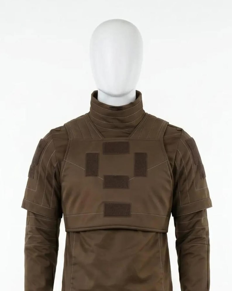 May include: A brown tactical vest with a high collar and shoulder pads, displayed on a mannequin. The vest features multiple rectangular patches and a layered design. The long-sleeved garment is a solid brown color, suitable for military or tactical applications.