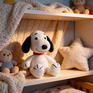 May include: A white crocheted Snoopy plush toy with black ears and a red collar sits on a shelf. A white star-shaped pillow and a teddy bear are also on the shelf. The shelf is part of a child's room.