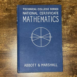 以下が含まれることがあります： テクニカルカレッジシリーズの「数学」というタイトルの青い教科書。表紙には白い文字と幾何学模様が描かれています。著者名であるAbbott & Marshallは下部に印刷されています。