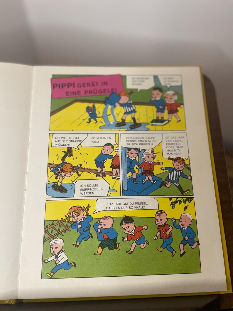 Puede incluir: Una p&aacute;gina de c&oacute;mic en alem&aacute;n. El t&iacute;tulo, en la parte superior, dice "PIPPI GERAT IN EINE PR&Uuml;GELEI!". Las ilustraciones coloridas muestran a ni&ntilde;os en diferentes escenas, con bocadillos de texto en alem&aacute;n. El estilo art&iacute;stico es animado y infantil.