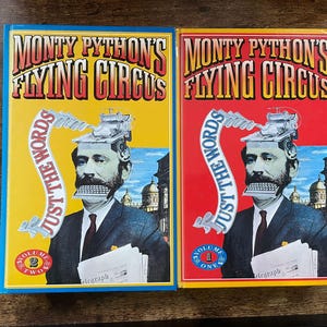 Peut inclure: Deux livres de Monty Python's Flying Circus, Volume 1 et Volume 2, avec des couvertures jaunes et rouges. Chacun présente un homme avec une machine à écrire à la place de la bouche et sur la tête. Le texte "Just the Words" est également visible.