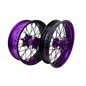 May include: Two motorcycle wheels, one in vibrant purple and the other in black. Both wheels feature a spoke design with a matching purple hub. The rims have a glossy finish, and the spokes are black, creating a striking contrast.