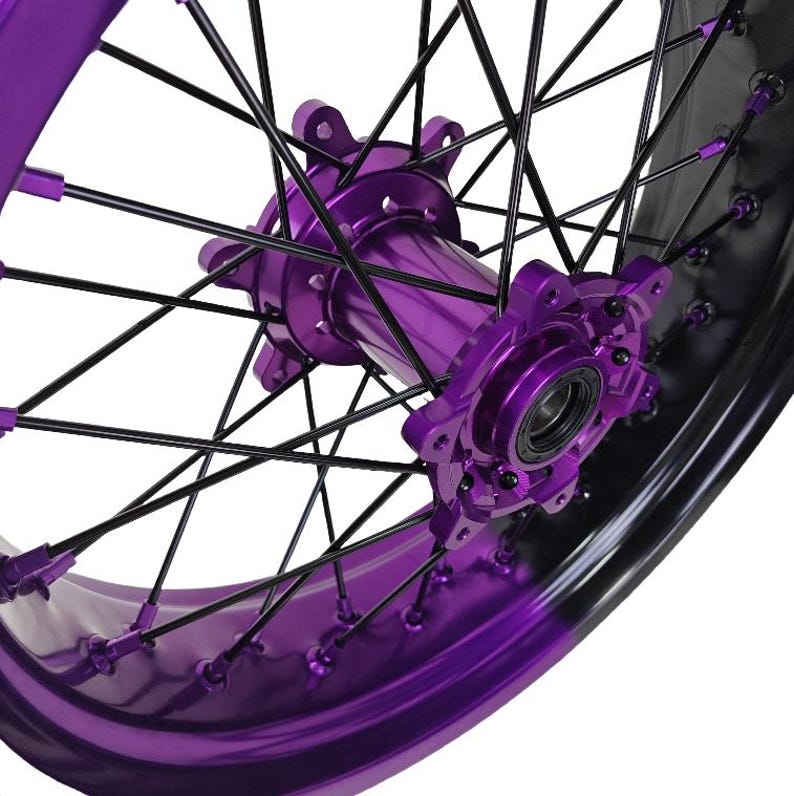 May include: Close-up of a motorcycle wheel with a vibrant purple hub and rim. The wheel features black spokes and a glossy finish, creating a striking contrast. The design highlights the intricate details of the wheel's construction.