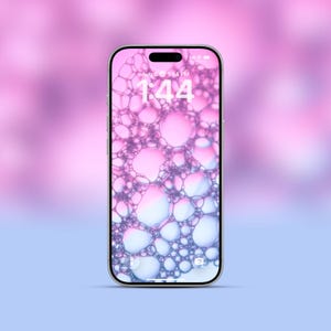Könnte beinhalten: Ein silbernes Smartphone zeigt einen Hintergrund mit Blasen in Rosa-, Lila- und Blautönen. Auf dem Bildschirm wird die Uhrzeit 13:44 Uhr am 6. August angezeigt. Das Telefon befindet sich vor einem verschwommenen rosa-blauen Hintergrund.