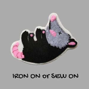 Pode incluir: Uma caneca de cerâmica branca com uma alça preta e o texto "But First, Coffee" em estilo manuscrito. A caneca está sobre uma superfície branca. A caneca tem aproximadamente 10 cm de altura.