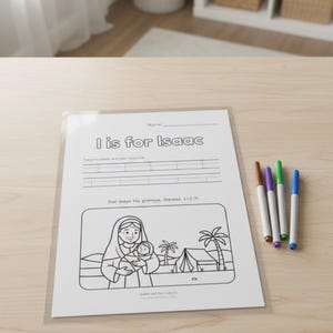 May include: A white worksheet with the text "I is for Isaac" and a black and white illustration of a woman holding a baby. Four colored markers are next to the worksheet.