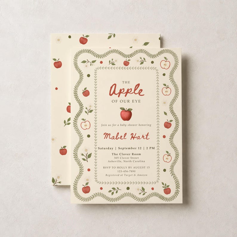 May include: A cream-colored baby shower invitation card featuring a scalloped green leaf border and red apple illustrations. The text reads: The Apple of our eye, join us for a baby shower honoring Mabel Hart, Saturday, September 12, 2 PM.