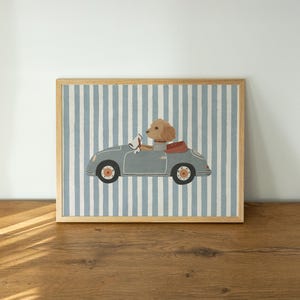 Puede incluir: Una impresión enmarcada que presenta un coche descapotable azul claro con un perro al volante. El coche está sobre un fondo de rayas verticales azules y blancas. La impresión tiene un marco de madera.