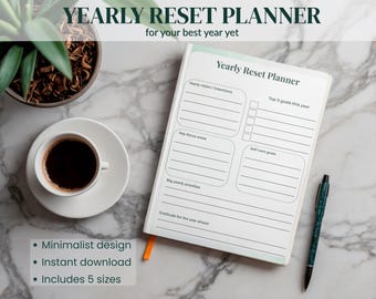 May include: A white Yearly Reset Planner with a minimalist design, open to a blank page. The planner is next to a cup of coffee, a pen, and a small plant. Text on the planner reads "Yearly Reset Planner" and "for your best year yet."