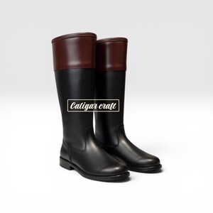 May include: A pair of tall black riding boots with brown leather tops. The boots have a classic design and are made of smooth leather. The text "Caligar craft" is displayed in a white box on the side of the boots.