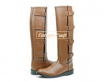 Könnte beinhalten: Ein Paar hohe braune Lederstiefel mit mehreren Schnallenriemen. Die Stiefel haben ein klassisches Design mit glatter Oberfläche und robuster Sohle. Der Text "Calogar Craft" ist auf den Stiefeln zu sehen.
