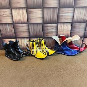 Könnte beinhalten: Eine Kollektion von Schuhen mit spitzer Zehenpartie in Schwarz, Gelb und Blau, jeweils mit hohem, geschwungenem Knöchelbereich und Schnürung. Die Schuhe sind in einer Reihe angeordnet und zeigen ihr markantes Design mit aufgebogener Spitze und glatter Oberfläche. Der Text Caligar Craft ist sichtbar.
