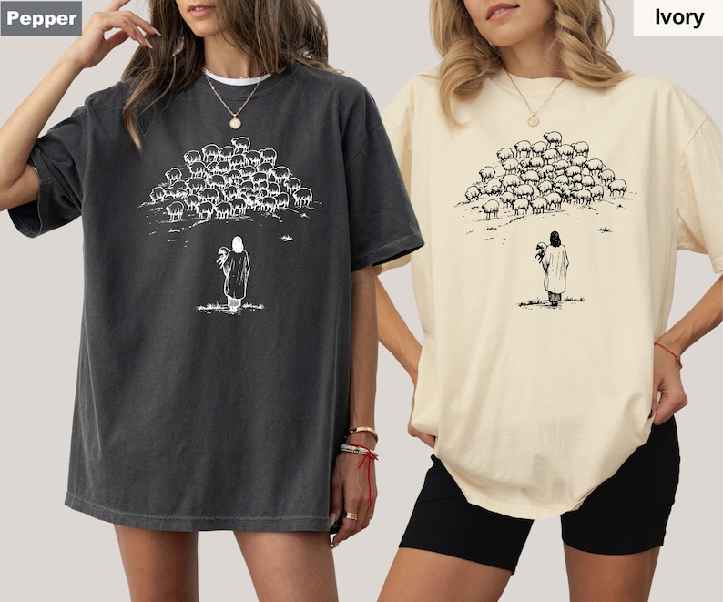 Op de afbeelding: Twee oversized T-shirts, &eacute;&eacute;n in peperkleur en &eacute;&eacute;n in ivoor, met een zwart-witte afbeelding. De afbeelding toont een persoon met een kudde schapen. De shirts hebben korte mouwen en een relaxte pasvorm.