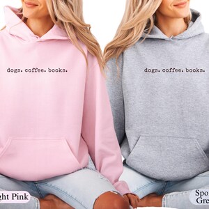May include: Light pink and sport grey hoodies with the text "dogs. coffee. books." printed in black. The hoodies have a front pocket and a hood with drawstrings. The light pink hoodie is on the left, and the sport grey hoodie is on the right.