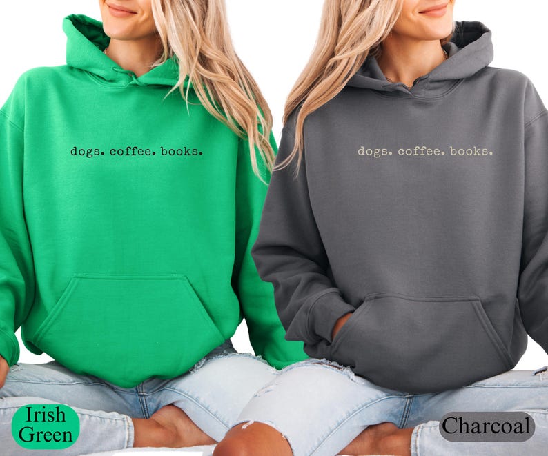 May include: Two hooded sweatshirts, one Irish green and one charcoal gray, are displayed. Each sweatshirt has a front pocket and the text "dogs. coffee. books." printed across the chest. The sweatshirts are shown on a person.