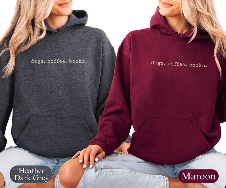 May include: Two hooded sweatshirts, one heather dark gray and one maroon, each with the text "dogs. coffee. books." in a simple, white font. The sweatshirts have a front pocket and a drawstring hood.