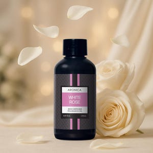 May include: A black bottle of "White Rose" reed diffuser fragrance oil by Aronica, with a white and pink label. The bottle is 4.05 fl oz and 120ml. White rose petals and a white rose are in the background.