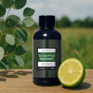May include: A black bottle of Aronica Eucalyptus Bergamot reed diffuser fragrance oil with a green and white label. A halved lime sits next to the bottle on a wooden surface. The bottle contains 4.05 fl oz (120ml).