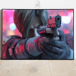 May include: A framed wall art print featuring a person aiming a red and black handgun. The person is in the foreground, with a blurred, colorful background. The print has a black frame and is displayed on a light wood surface.