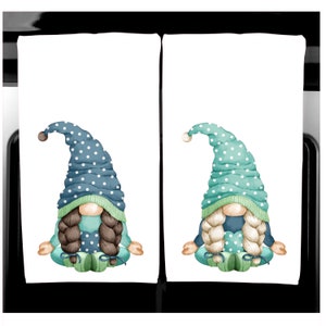 K&ouml;nnte beinhalten: Zwei wei&szlig;e K&uuml;chent&uuml;cher mit jeweils einem Aquarell-Zwergen-Design. Ein Zwerg tr&auml;gt einen blauen Hut mit wei&szlig;en Punkten, der andere einen t&uuml;rkisfarbenen Hut. Beide Zwerge haben geflochtenes Haar, t&uuml;rkisfarbene Kleidung und sitzen in einer Yoga-Pose.