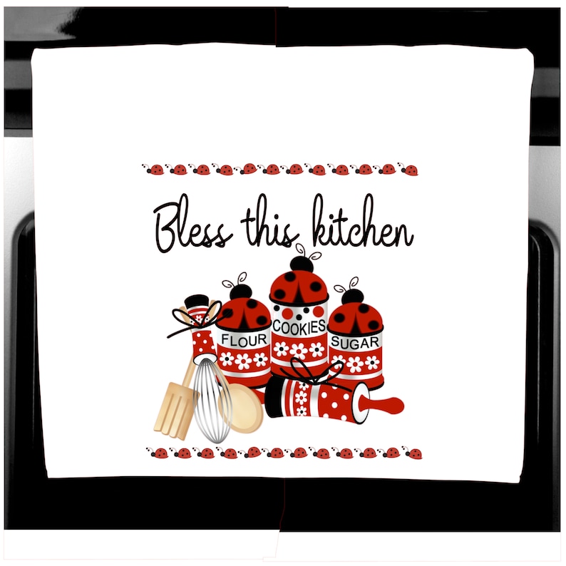 K&ouml;nnte beinhalten: Wei&szlig;es K&uuml;chentuch mit einem skurrilen Design. Es zeigt rot-wei&szlig;e Gl&auml;ser mit den Aufschriften "FLOUR", "COOKIES" und "SUGAR", verziert mit Marienk&auml;fer-Akzenten. Der Text "Bless this kitchen" steht oben.