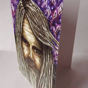May include: A black and white drawing of a person with long, flowing hair. The person has a beard and a serious expression. The background is a purple and white pattern with runes.