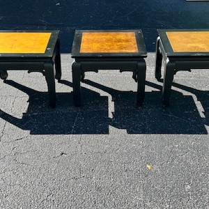 May include: Three black end tables with gold tops. The tables have a traditional Asian design with curved legs.