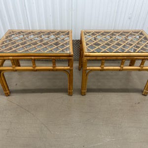 May include: Two matching natural bamboo end tables with glass tops. The tables have a woven lattice design and are perfect for a living room or bedroom.