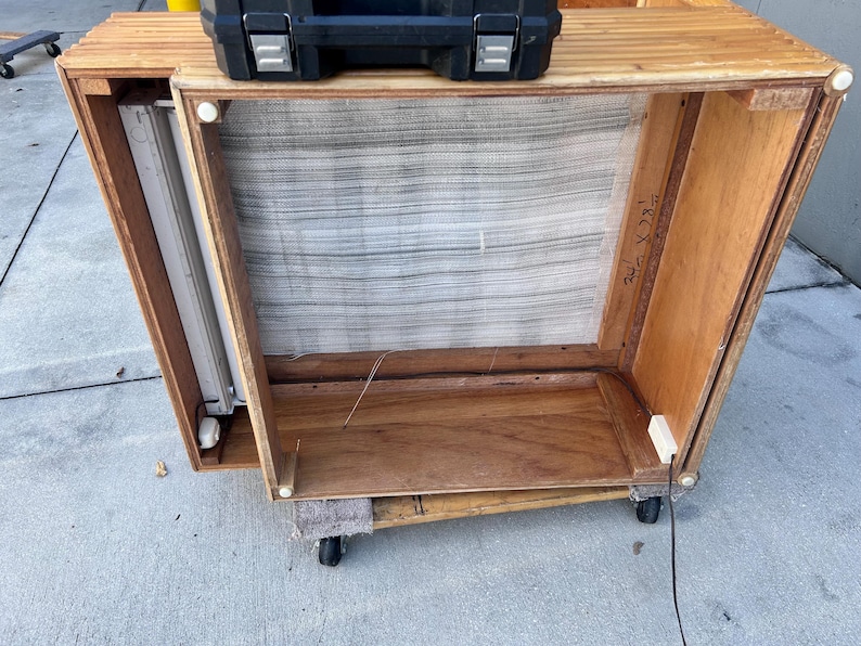 May include: A wooden cabinet with a mesh screen and a fluorescent light fixture inside. The cabinet is on wheels and has a black case on top. The dimensions are marked as 24" x 34".