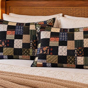 Puede incluir: Dos fundas de almohada rectangulares con un diseño de patchwork compuesto por varios cuadrados de tela en tonos negro, crema, verde oliva y azul marino. La tela muestra diversos patrones florales, geométricos y sólidos con costuras visibles.