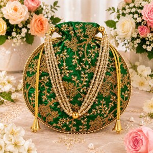 Op de afbeelding: Een ronde groene tas met trekkoordsluiting en ingewikkeld goudkleurig borduurwerk in een bloemmotief. De tas is versierd met een meerstrengs parelhandvat en goudkleurige metalen accenten, waaronder twee decoratieve kwastjes aan de zijkanten.