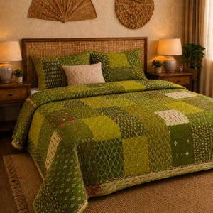 Peut inclure: Un couvre-lit en patchwork composé de différentes nuances de vert avec des motifs géométriques blancs et vert foncé. Le couvre-lit recouvre un lit et comprend deux taies d'oreiller assorties ainsi qu'un coussin rectangulaire beige au centre.