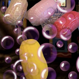 Può includere: Quattro oggetti ovali e testurizzati di colore beige, rosa chiaro, rosso e giallo, ciascuno avvolto singolarmente in plastica trasparente. Gli oggetti sono disposti in gruppo, parzialmente oscurati da diverse bolle viola traslucide.