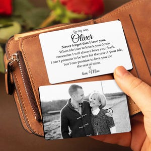 May include: A brown leather wallet with a personalized card. The card has a black and white photo of a man and woman, and text that reads "To my son Oliver, Never forget that I love you...love, Mom."