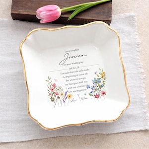 May include: A square white ceramic trinket dish with a scalloped edge and a gold-painted rim. The center features a floral design and text that reads: To my Daughter Jessica On your Wedding day 09.02.26 The walk down the aisle marks the beginning of a new life. But wherever you go, my heart goes with you. I wish you a lifetime of love and happiness. Love, Mom.