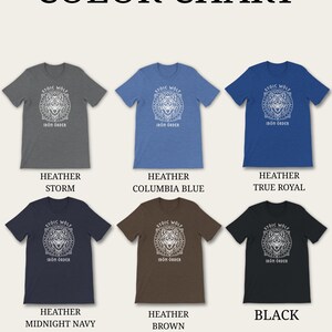 以下が含まれることがあります： さまざまな色の6枚のTシャツを紹介するカラーチャート。ヘザーストーム、ヘザーコロンビアブルー、ヘザートゥルーロイヤル、ヘザーミッドナイトネイビー、ヘザーブラウン、ブラック。各シャツには白いオオカミのグラフィックと「STOIC WOLF IRON ORDER」の文字が描かれています。