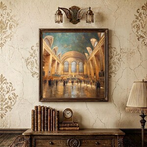 May include: A square framed oil painting depicting the interior of Grand Central Terminal with a high vaulted ceiling, arched windows, and a crowd of people walking across the floor. The artwork is displayed on a wall above a wooden console table.