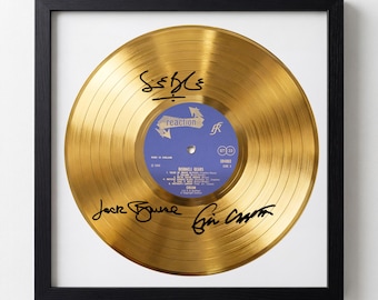 May include: A framed, gold-colored vinyl record with black signatures. The record has a blue and white label with the text "reaction" and "Disraeli Gears". The frame is black and square.
