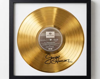 May include: Framed gold record with a black frame. The record has a label that reads "Parlophone" and "All Things Must Pass" by George Harrison. The record is signed "George Harrison".