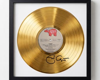 May include: Framed gold record with a black frame. The record has a gold finish and a label with the text "RSO" and a red pig illustration. The record is signed in black ink. The frame is square.