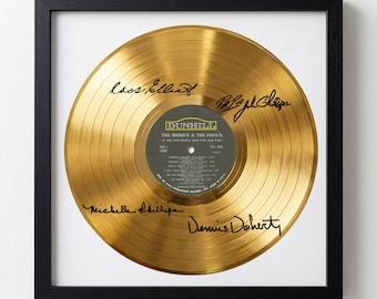 May include: Framed gold record of The Mamas & the Papas album, signed by the band members. The record is displayed in a black frame with a white mat. The record label is visible in the center.
