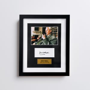 Puede incluir: Fotografía enmarcada de J.R.R. Tolkien, con su firma y una placa que dice "J.R.R. Tolkien, escritor y filólogo inglés". El marco es negro, con un paspartú negro.