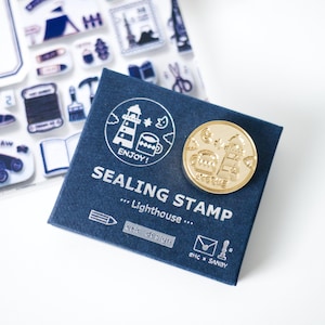 May include: A navy blue sealing stamp set with a gold-colored stamp and a matching navy blue box. The box has a lighthouse graphic and the words "SEALING STAMP ... Lighthouse..." printed on it. The stamp has a lighthouse and other graphics.