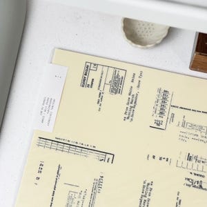 May include: An overhead view of vintage stationery. The image shows several sheets of paper with printed text and graphics, including a coupon and text that reads "Wedding March". The paper has a slightly aged, off-white colour, suggesting a retro aesthetic.