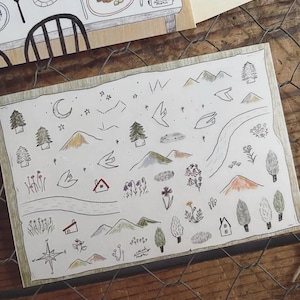 Puede incluir: Ilustración dibujada a mano que representa un paisaje con montañas, árboles, un río y una rosa de los vientos. La obra de arte incluye una luna creciente, estrellas y pequeñas casas, todo en una paleta de colores apagados.