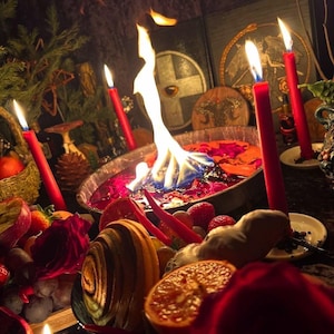 May include: A mystical scene featuring a central bowl with flames, surrounded by red candles, fruits, and other ritualistic items. The bowl contains colorful liquids, and the scene is dimly lit, creating a mysterious atmosphere.