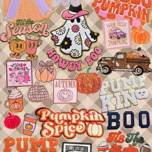 May include: A collection of embroidered patches featuring autumn and Halloween themes, including pumpkins, ghosts wearing cowboy hats, trucks, coffee cups, and text such as Hello Pumpkin, Howdy Boo, Pumpkin Spice, and Tis the Season.