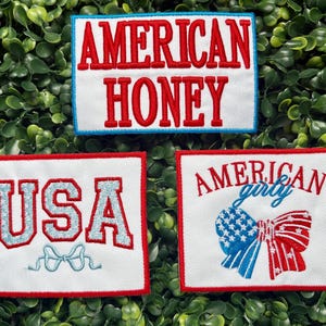 May include: Three embroidered patches with patriotic themes. One patch reads "AMERICAN HONEY" in red letters with a blue border. Another says "USA" in light blue with a bow. The third patch says "AMERICAN girly" with a red, white, and blue bow.