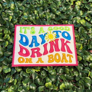 May include: Embroidered patch with the text "IT'S A GOOD DAY TO DRINK ON A BOAT" in bright colors. The patch has a white background with a pink border and a yellow sun graphic.
