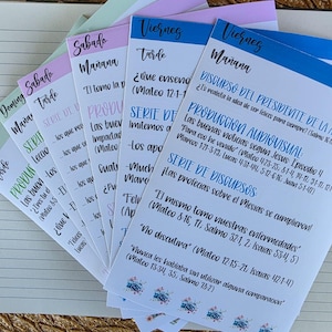 May include: A stack of colorful paper cards with handwritten text in Spanish. The cards are labeled with days of the week and include text about sermons and biblical verses. Floral designs decorate the bottom of some cards.
